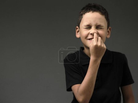 Téléchargez les photos : Garçon piquer son nez avec fond sombre - en image libre de droit