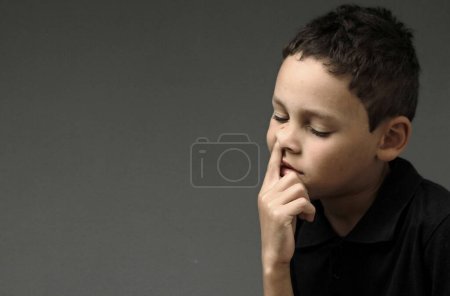 Téléchargez les photos : Garçon piquer son nez avec fond sombre - en image libre de droit