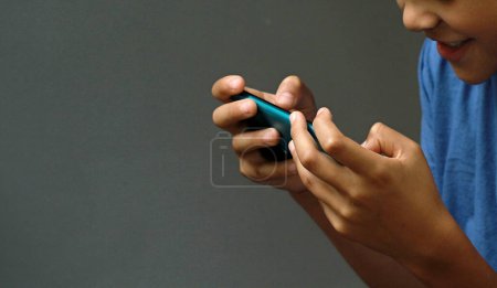 Photo for Boy making a phone call on his mobile phone with grey background - Royalty Free Image