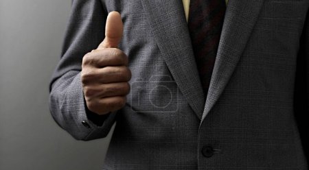 Photo for Businessman giving thumbs up on black background - Royalty Free Image