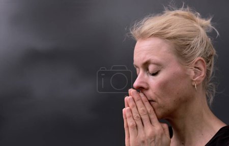 Foto de Mujer rezando a Dios con las manos juntas sobre fondo negro gris con la gente stock imagen de stock foto - Imagen libre de derechos