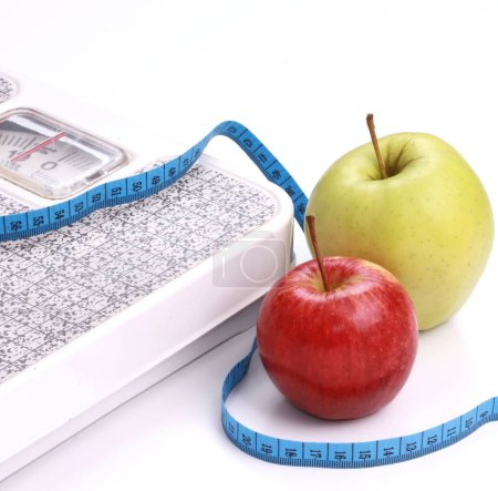 Foto de Perder peso pesando balanza y comer sano en el nuevo año a partir de unas deliciosas manzanas - Imagen libre de derechos