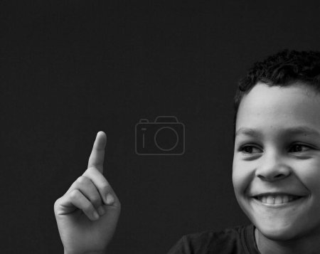 Téléchargez les photos : Enfant pointant et atteignant le ciel sur fond gris - en image libre de droit