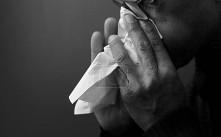 Téléchargez les photos : Nez soufflant après avoir attrapé la grippe et froid avec fond gris - en image libre de droit