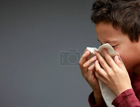 Foto de Problemas respiratorios asmáticos para atrapar al niño con gripe que sopla la nariz después de tener un resfriado con fondo gris con la foto de la gente - Imagen libre de derechos