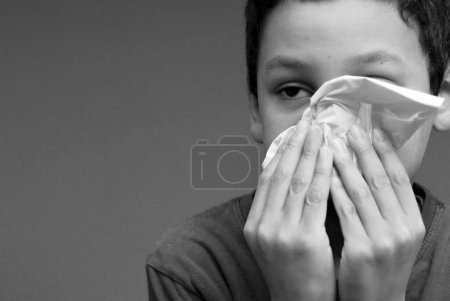Foto de Chico soplando la nariz después de coger un resfriado - Imagen libre de derechos