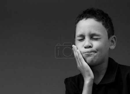 Photo for Boy with toothache boy in pain on grey background - Royalty Free Image