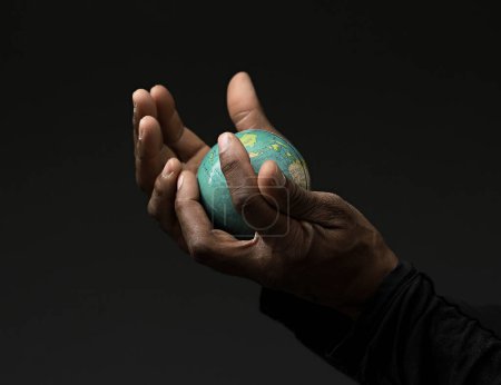 Téléchargez les photos : Homme noir priant Dieu avec globe à la main avec des gens sur fond gris noir - en image libre de droit