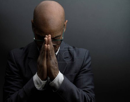 Foto de Hombre negro rezando a Dios con fondo gris negro - Imagen libre de derechos