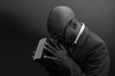 Foto de Hombre negro rezando a Dios con fondo gris negro - Imagen libre de derechos