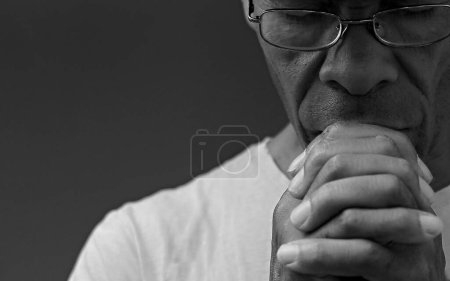 Téléchargez les photos : Noir caribéen homme priant dieu sur fond noir - en image libre de droit