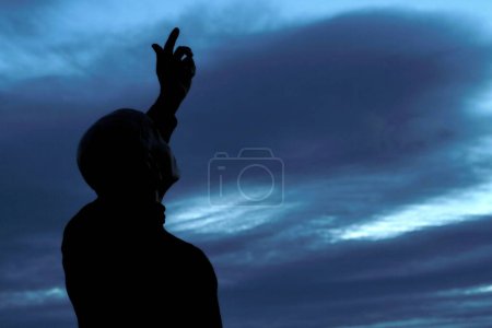 Photo for Black man praying to god with arms outstretched looking up to the sky - Royalty Free Image