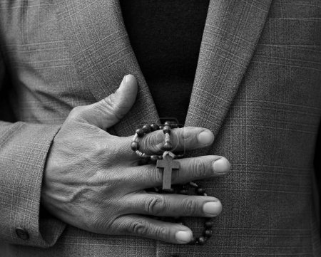 Photo for Man praying to God with with cross on black background - Royalty Free Image