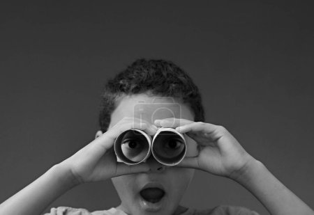 Photo for Boy looking through binoculars made from toilet paper rolls on grey background - Royalty Free Image
