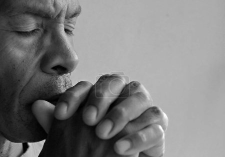 Téléchargez les photos : Homme priant dieu sur fond gris noir - en image libre de droit