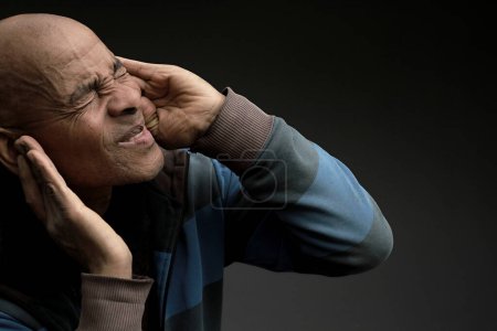man suffering from deafness and hearing loss on grey background