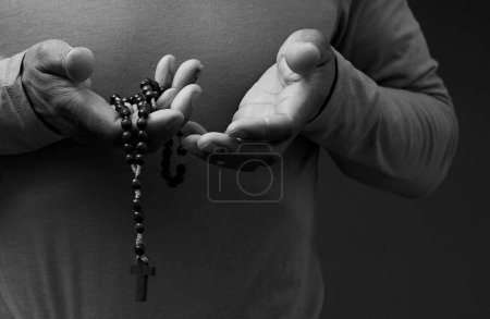 Foto de Sacerdote con rosarios rezando sobre fondo oscuro, primer plano - Imagen libre de derechos