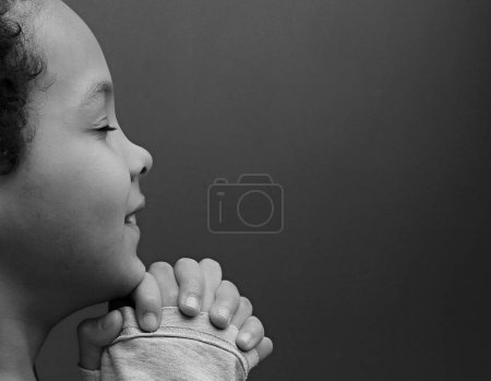 Foto de Niño rezando a Dios con las manos juntas sobre fondo blanco - Imagen libre de derechos