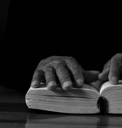 Photo for Black man praying god with bible in hands. Caribbean man praying on black background, cropped section - Royalty Free Image