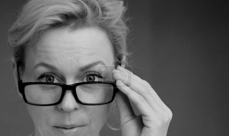 Téléchargez les photos : Femme avec des lunettes touchantes sur fond gris, photo de studio - en image libre de droit