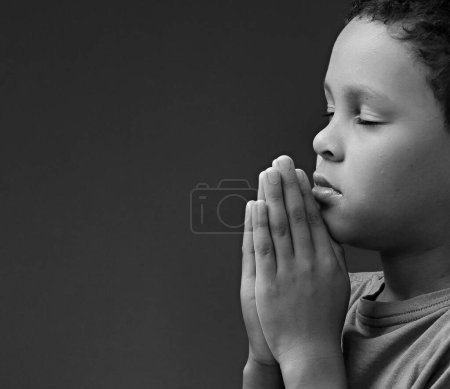 Foto de Niño rezando a Dios con las manos juntas sobre fondo blanco - Imagen libre de derechos