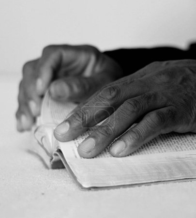 Foto de Hombre negro rezando a Dios con la Biblia en las manos. Hombre caribeño rezando sobre fondo negro, sección recortada - Imagen libre de derechos