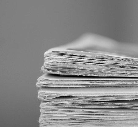 Téléchargez les photos : Journaux empilés sur la table dans le bureau avec fond blanc - en image libre de droit