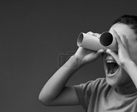 Child boy looking through binoculars toilet paper rolls on white background