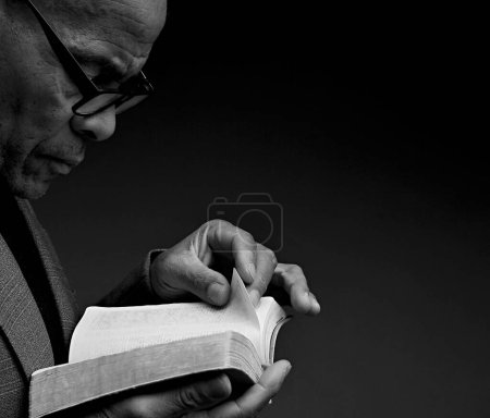 Téléchargez les photos : Homme noir priant Dieu avec la bible dans les mains. Homme des Caraïbes priant sur fond noir, section coupée - en image libre de droit