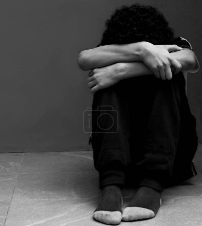 Boy praying in poverty on floor, studio portrait 