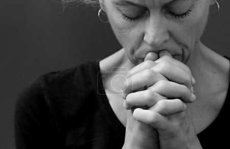 Téléchargez les photos : Femme priant avec les mains pliées sur fond gris noir - en image libre de droit