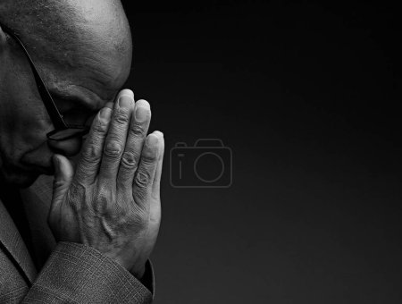 Photo for Caribbean man praying to god with hands together, black and white studio photo - Royalty Free Image