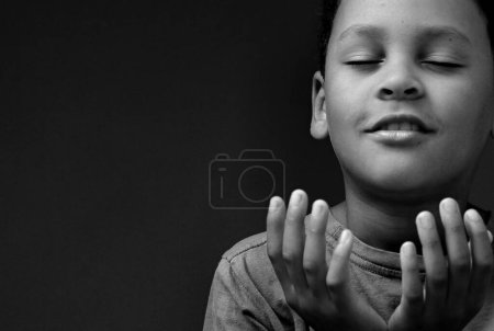 Photo for Boy praying in poverty on floor, studio portrait - Royalty Free Image