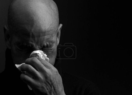 Man catching cold and flu man blowing nose after catching a cold, studio shot 