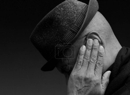Deaf man suffering from deafness and hearing loss. Black and white image