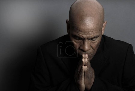 Téléchargez les photos : Homme priant Dieu sur fond noir - en image libre de droit