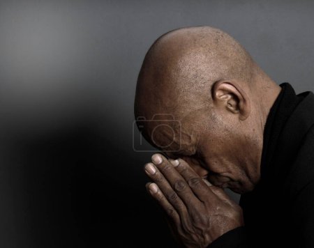 Téléchargez les photos : Homme priant Dieu sur fond noir - en image libre de droit