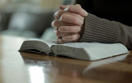 Photo for Woman praying to god with bible while sitting on the wooden table, closeup - Royalty Free Image