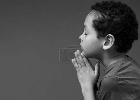 Photo for Portrait of little boy praying to god on dark background in studio, black and white - Royalty Free Image