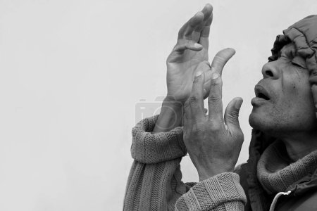 Téléchargez les photos : Homme à la cagoule priant Dieu avec les mains sur fond blanc, noir et blanc - en image libre de droit