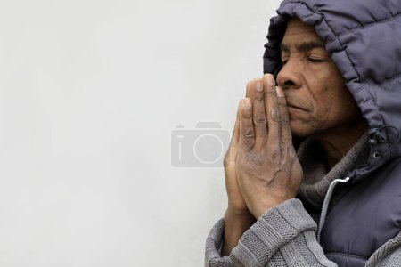 Foto de Hombre en la capucha rezando a Dios con las manos sobre fondo blanco - Imagen libre de derechos