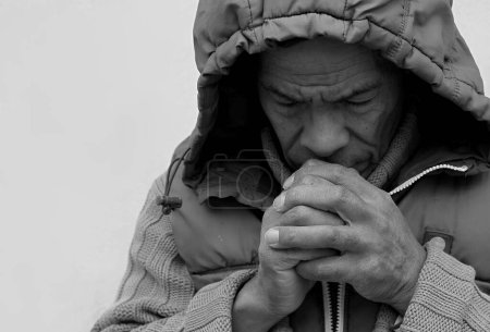 Foto de Hombre en la capucha rezando a Dios con las manos sobre fondo blanco, blanco y negro - Imagen libre de derechos