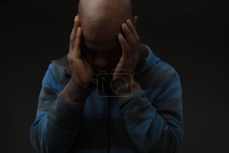 Foto de Hombre que sufre de sordera y pérdida auditiva oídos cerrados con las manos en el fondo oscuro - Imagen libre de derechos