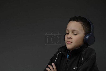 Téléchargez les photos : Garçon dans casque profiter de la musique sur fond sombre - en image libre de droit