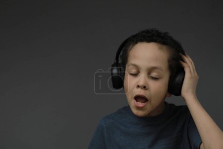 Photo for Boy in headphones enjoying music on dark background - Royalty Free Image