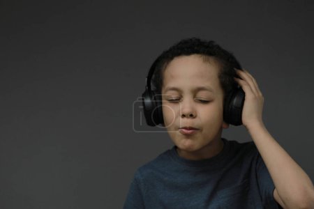 Photo for Boy in headphones enjoying music on dark background - Royalty Free Image