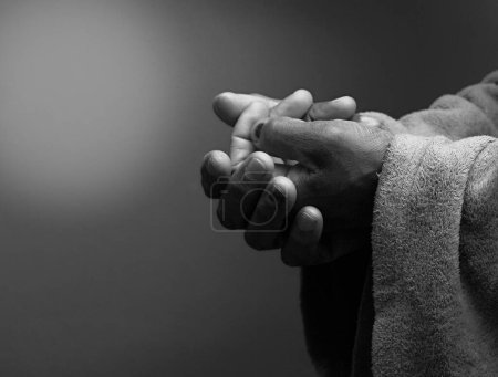 Téléchargez les photos : Homme priant Dieu avec les mains ensemble sur fond sombre - en image libre de droit