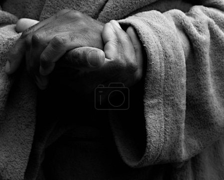 Photo for Man praying to god with hands together on dark background - Royalty Free Image