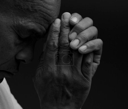 Téléchargez les photos : Homme priant Dieu avec les mains sur fond sombre - en image libre de droit