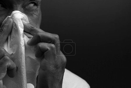 Foto de Hombre soplando la nariz después de coger un resfriado con fondo oscuro - Imagen libre de derechos